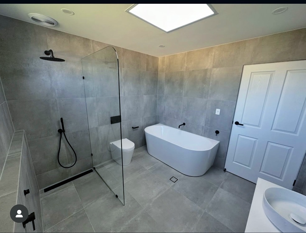 Modern bathroom with grey tiles and freestanding bathtub
