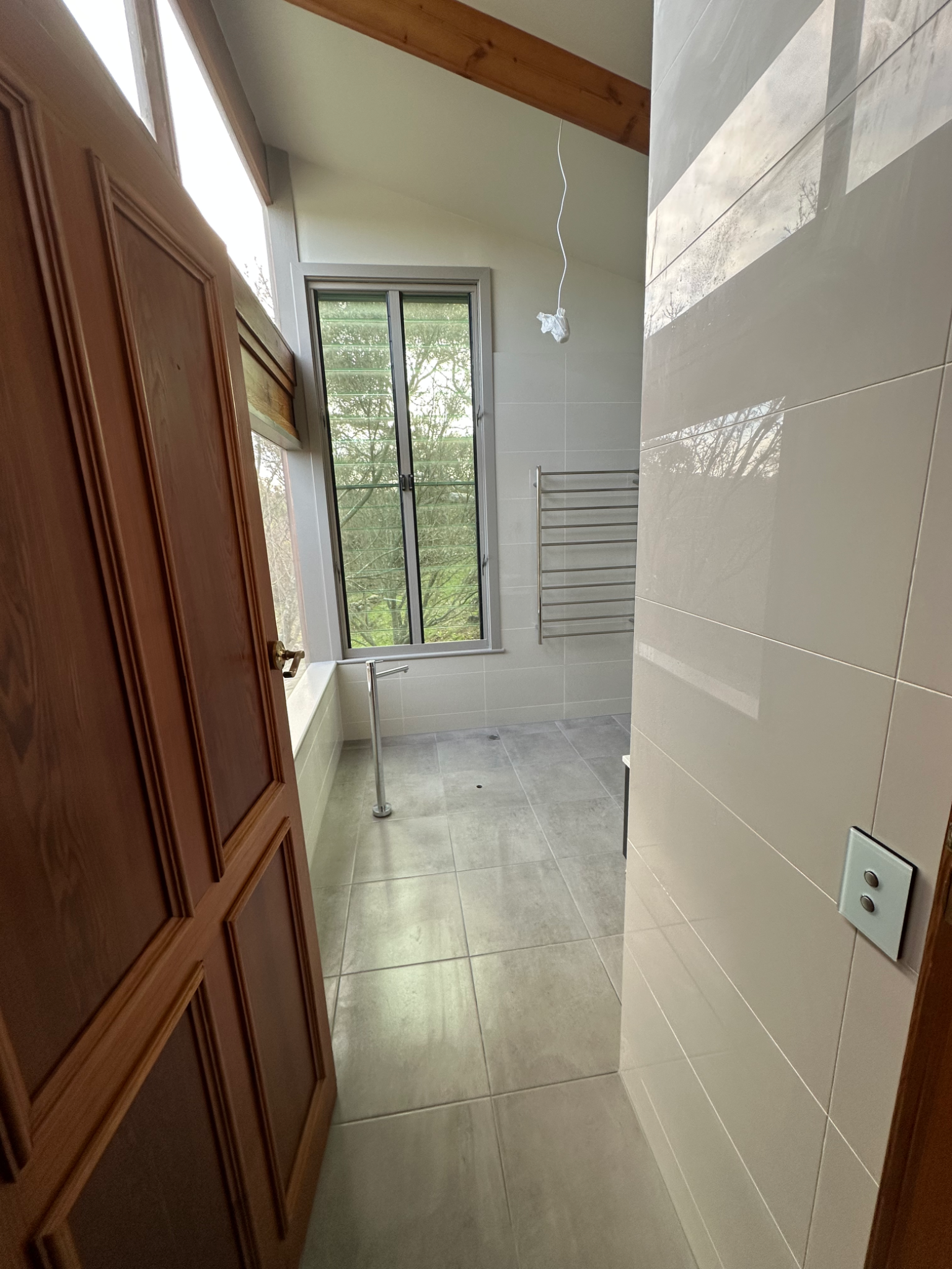 Bathroom renovation in progress with timber door and tiled floor